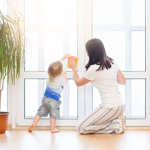 Fenster putzen, Frau mit Kleinkind, großes Fenster im Zimmer