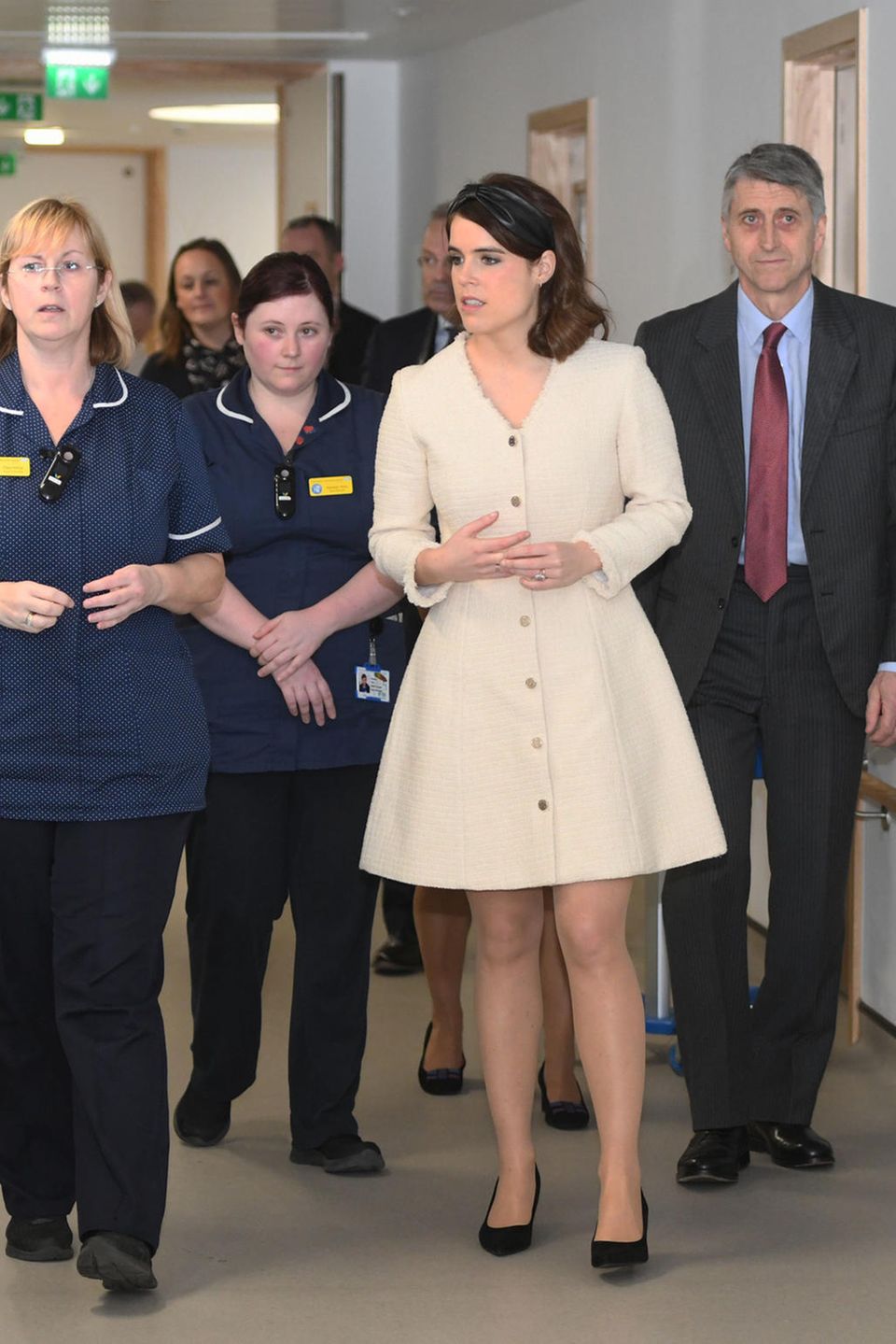 In einem kurzen, beigefarbenen Kleid mit auffälliger Knopfleiste zeigt Eugenie bei einem Krankenhausbesuch ganz schön viel Bein. 