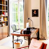 Seinen schmalen und mit gerahmten Fotografien dekorierten Schreibtisch hat König Willem-Alexander vor der großen Fensterfront positioniert, um so die wunderschöne Aussicht auf die Parkanlage genießen zu können. Helle Beigetöne und edles Holz bestimmen sein Interieur.