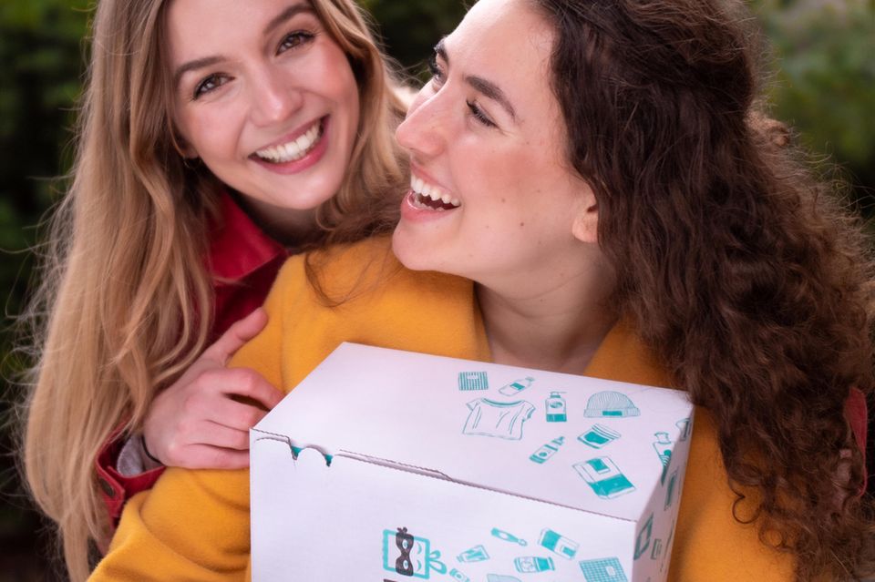 Frauen lächeln sich an und halten Box in den Händen Frauen lächeln sich an und halten Box in den Händen
