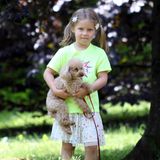 Tochter Celeste spielt mit Hündchen Lilly auf der Wiese.