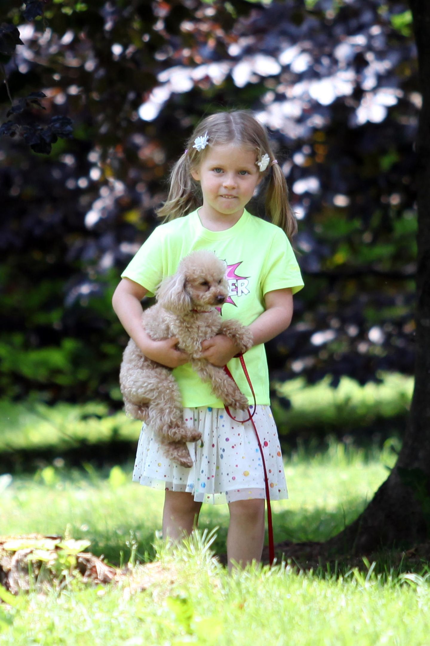 Tochter Celeste spielt mit Hündchen Lilly auf der Wiese.