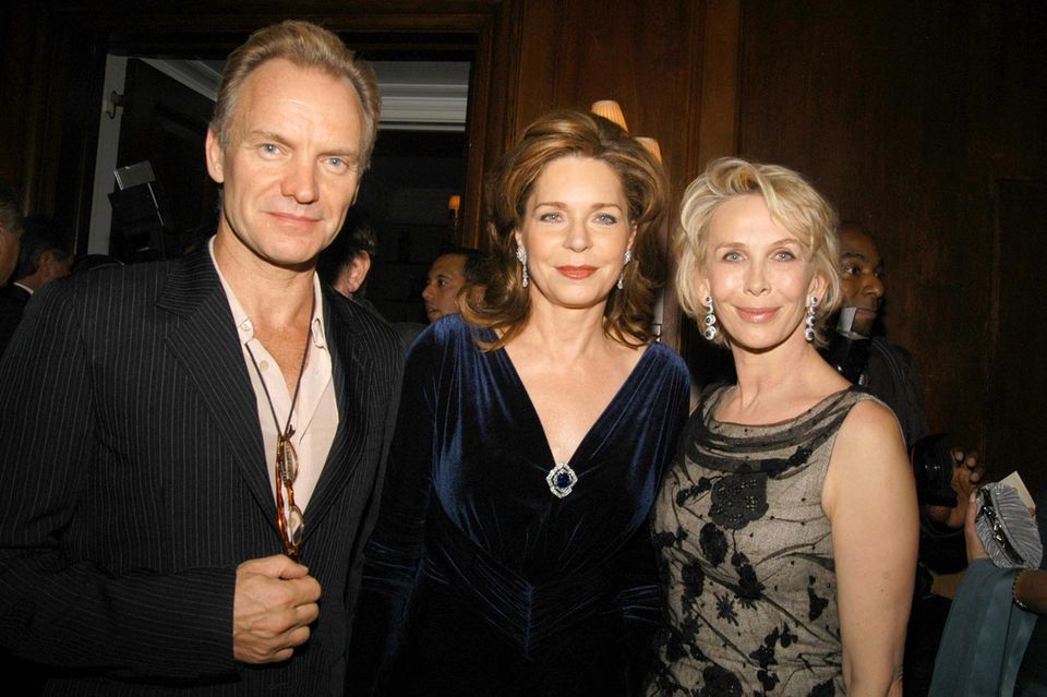Königin Noor (Mitte) mit Sänger Sting und Schauspielerin Trudie Styler bei einem Dinner in New York im November 2005. Im tiefen Ausschnitt ihres samtblauen Kleides steckt die Brosche mit dem blauen Saphir. 