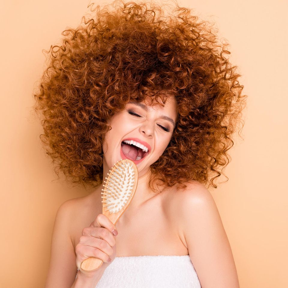 Frau sing mit Bürste als Mikrofon, Lockenkopf