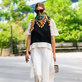 Reduzierte klassische Schwarz-Weiß-Looks lockert Olivia Palermo mit farbenfrohen Design-Schals auf, die sie zum Dreieck gebunden über Nase und Mund trägt. 