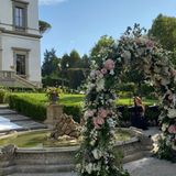 Wie aus einem Märchen! Die Hochzeit findet im Freien statt, vor einem Brunnen ist der Bogen aufgestellt, unter dem Sylvie Meis und Niclas Castello zum Ehepaar werden. Rosafarbene und weiße Blumen sind dort angesteckt. Im Hintergrund ist die Villa Cora, ein ehemaliger Adelssitz, am Ende des 19. Jahrhunderts gebaut, zu sehen. 