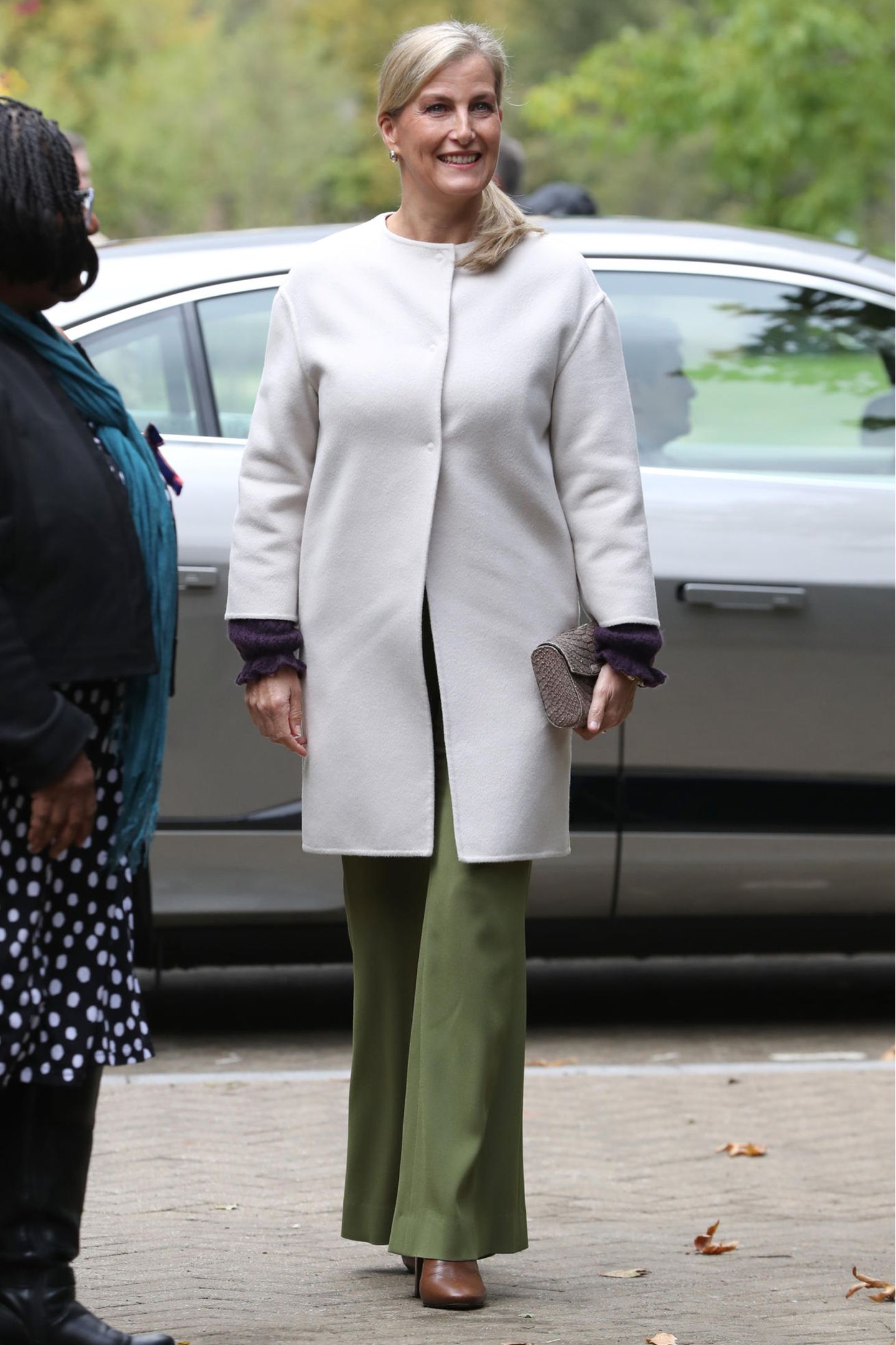 Den Rest des Looks hält die Gräfin eher schlicht. Sie trägt eine khakifarbene Hose mit ausgestelltem Bein und braune Stiefel. Dazu kombiniert sie einen cremeweißen Mantel. 