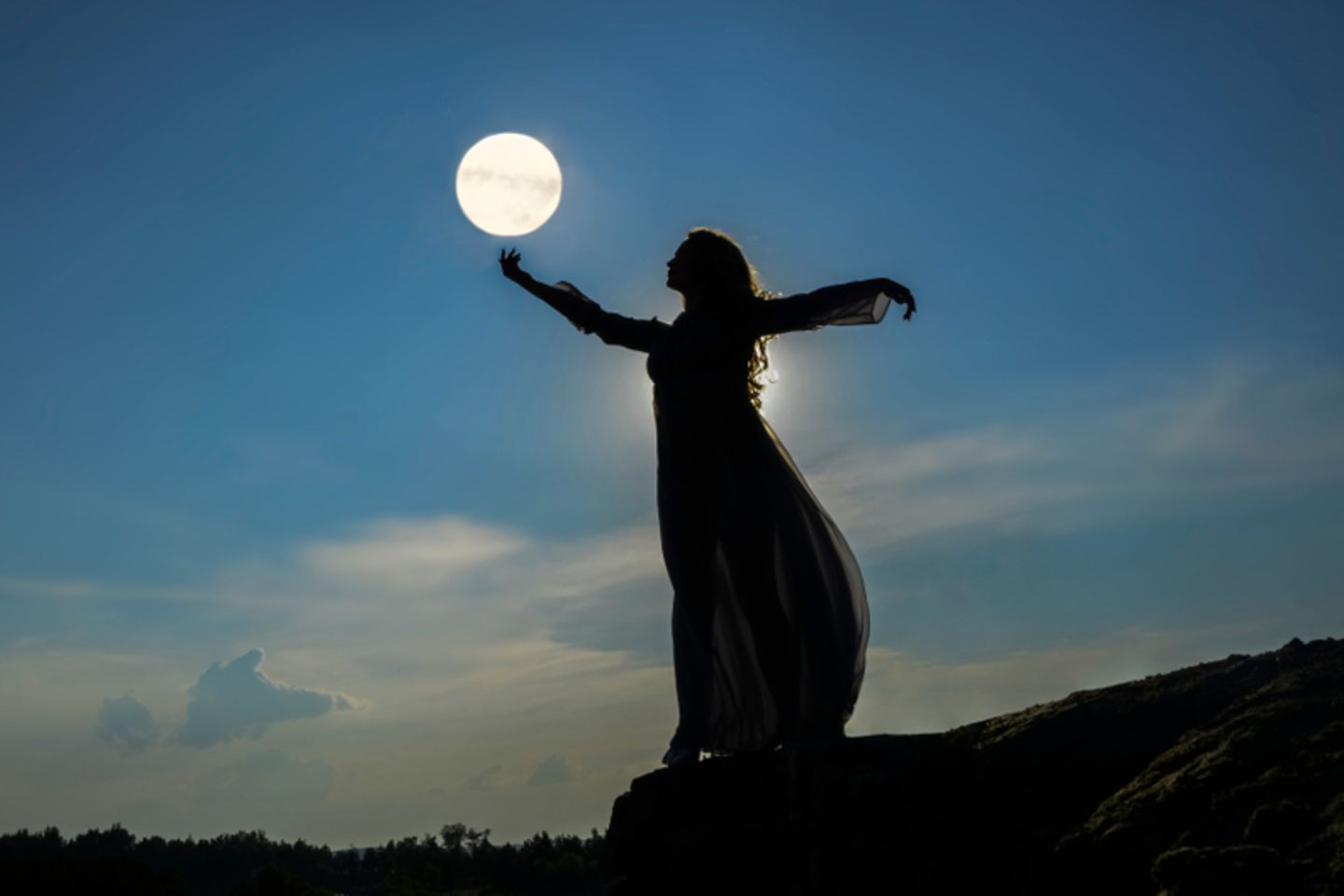 Mondzeichen: Die Silhouette einer Frau vor dem Abendhimmel.