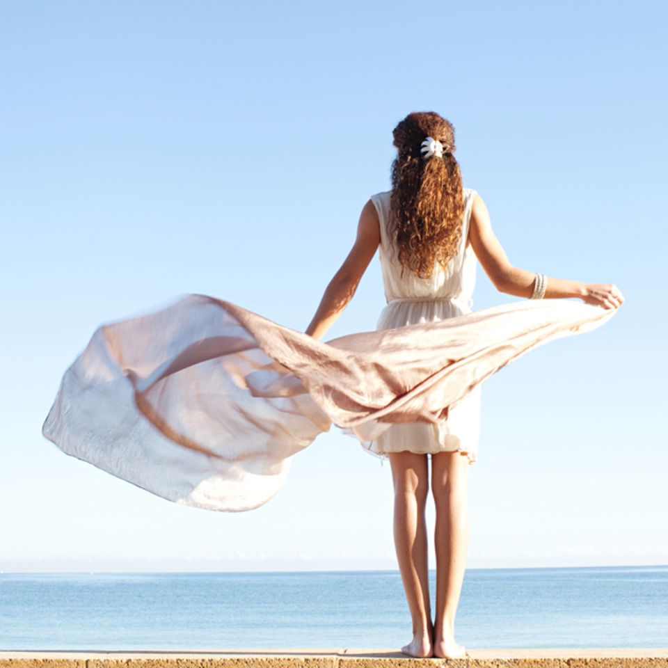 Luftzeichen: Frau mit langem Kleid, das im Wind weht.
