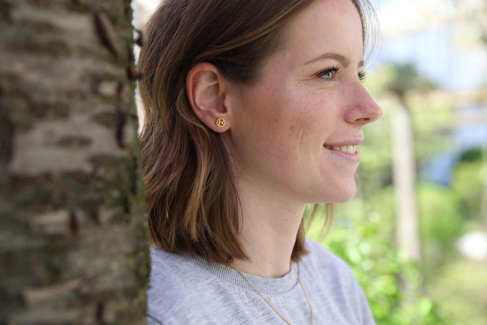 Junge Frau trägt Diamond Ohrstecker in Gold Junge Frau trägt Diamond Ohrstecker in Gold