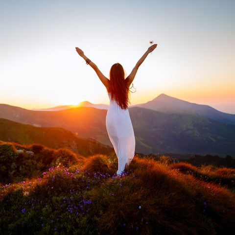 Erdzeichen: Frau auf einem Hügel mit Sonnenuntergang