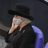 Unter den Zuhörern im Plenarsaal befindet sich auch Herzogin Camilla, die mit Hut und Maske interessiert den Worten ihres Gemahls lauscht.