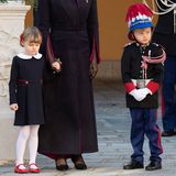 In ihren schicken Feiertagsoutfits wirken Prinzessin Gabriella und Prinz Jacques von Monaco fast ein bisschen verkleidet. Während Gabriella an der Hand von Mama Charlène ein blaues Kleid mit Bubikragen und eine weiße Strumpfhose trägt, zeigt sich der junge Prinz von Kopf bis Fuß in Uniform. 