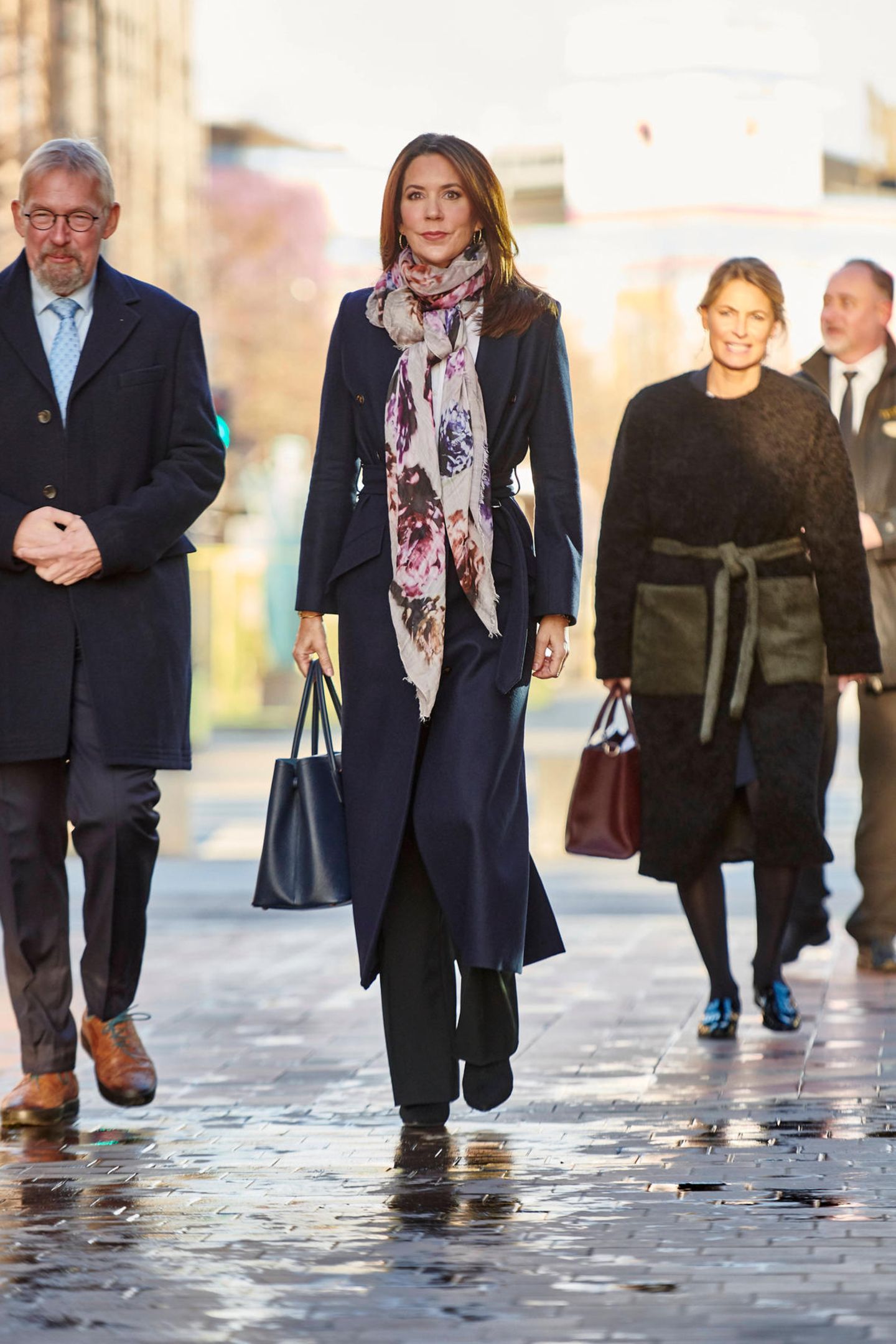 Prinzessin Mary ist anlässlich des Weltkindertags in Kopenhagen unterwegs. Sie trägt einen schicken dunklen Mantel von Fonnesbech, einem nachhaltigen dänischen Label, Stiefeletten des spanischen Labels Pura Lopez und eine dunkle Leder-Handtasche von Prada. Als farbigen Eyecatcher wählt sie ein gemustertes Tuch. 