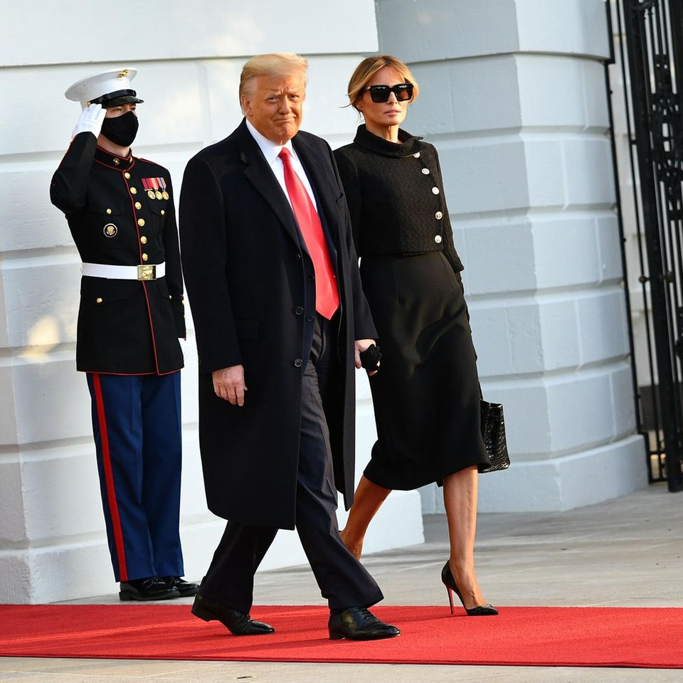 Fashion-Looks: Ein historischer Moment: Donald Trump und Melania Trump verlassen das Weiße Haus. Für ihren letzten Auftritt als First Lady setzt Melania auf ein komplett schwarzes Outfit bestehend aus einer Chanel-Jacke mit seitlicher Knopfleiste und schienbeinlangem Kleid. Eine elegante Hochsteckfrisur rundet den "Trauer"-Look ab. Ein historischer Moment: Donald Trump und Melania Trump verlassen das Weiße Haus. Für ihren letzten Auftritt als First Lady setzt Melania auf ein komplett schwarzes Outfit bestehend aus einer Chanel-Jacke mit seitlicher Knopfleiste und schienbeinlangem Kleid. Eine elegante Hochsteckfrisur rundet den "Trauer"-Look ab.