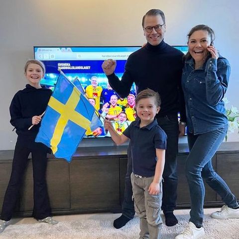 Prinz Frederik telefoniert mit Prinzessin Victoria, die mit Prinzessin Estelle, Prinz Oscar und Ehemann Prinz Daniel im Wohnzimmer steht.