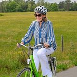 Für eine Radtour mit der Familie kann auch auch mal lässig zugehen: Die sommerliche weiße Hose kombiniert sie mit passenden Turnschuhen und folkloristischer Bluse.