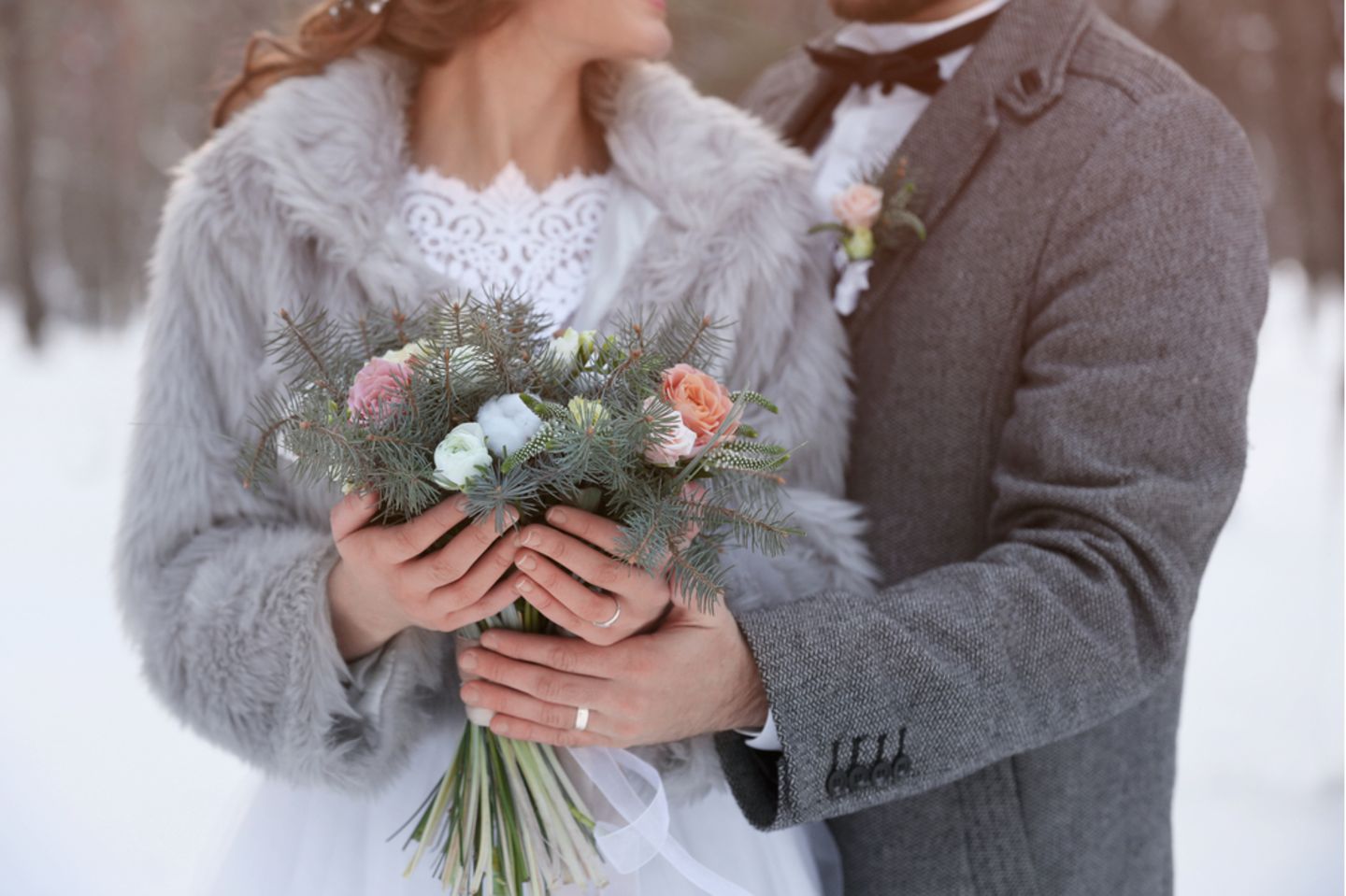 Winterhochzeit: Braut und Bräutigam halten einen winterlichen Brautstrauß