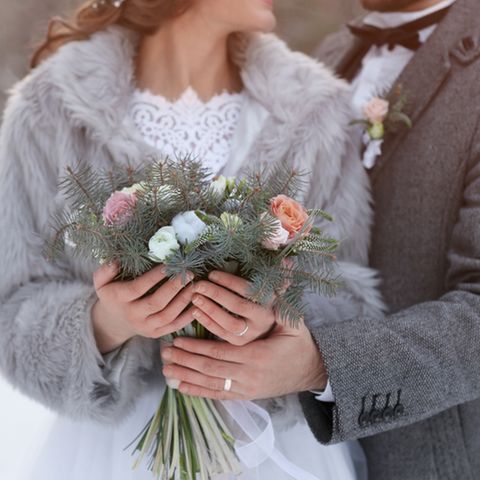 Winterhochzeit: Braut und Bräutigam halten einen winterlichen Brautstrauß