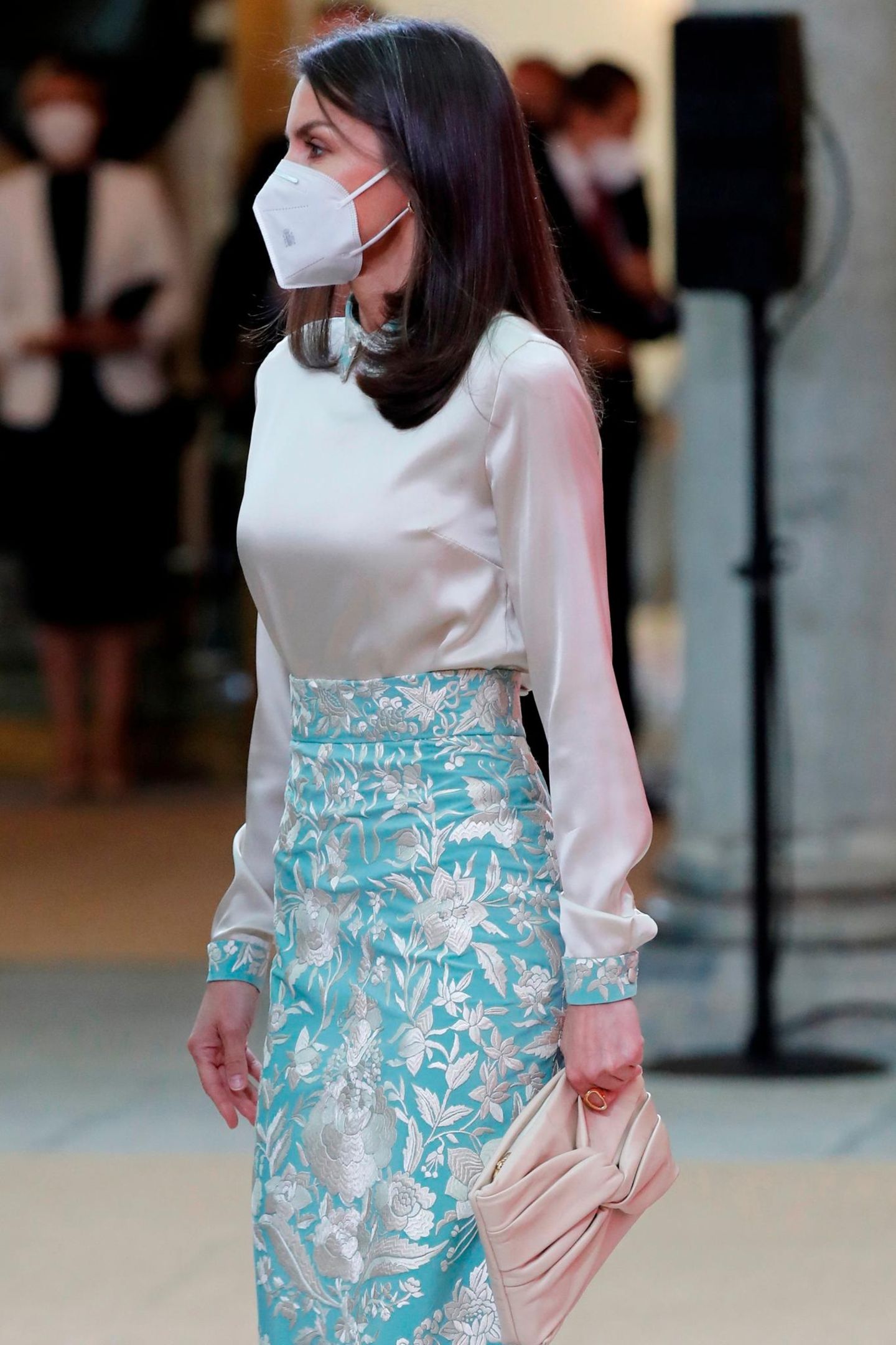 In Kragen und Bündchen der cremefarbenen Bluse wird das Muster wieder aufgegriffen. Dazu trägt Königin Letizia eine beigefarbene Clutch.