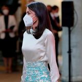 In Kragen und Bündchen der cremefarbenen Bluse wird das Muster wieder aufgegriffen. Dazu trägt Königin Letizia eine beigefarbene Clutch.