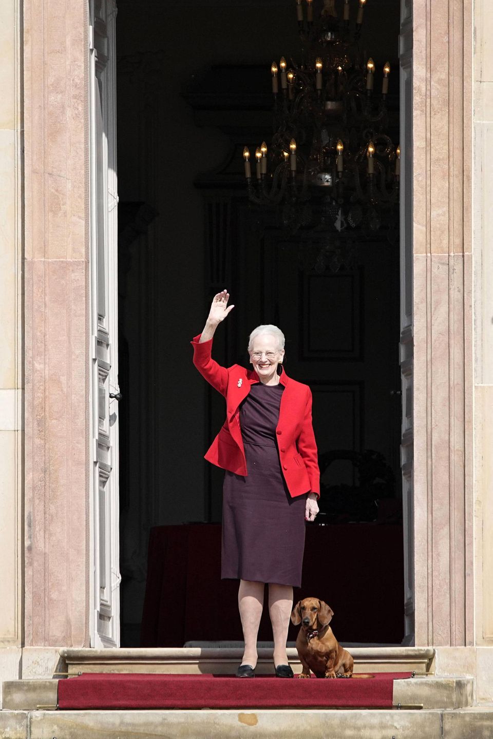 16. April 2021  Mit einem großen Lächeln im Gesicht winkt Königin Margrethe von Dänemark ihren Gratulanten vor Schloss Fredensborg zu. An diesem Tag feiert sie ihren 81. Geburtstag und lässt sich bei strahlendem Sonnenschein auf der Schlosstreppe blicken. Doch sie ist nicht allein: Begleitet wird sie von ihrem Lieblingsdackel, der brav neben der Königin wartet, während sie sich all die Glückwünsche aus der Ferne abholt.