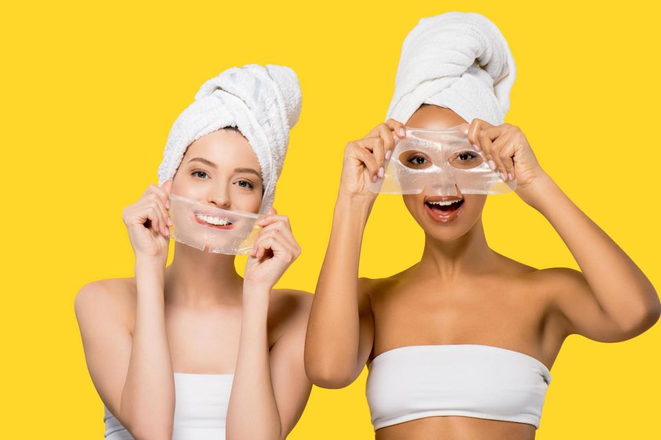 Fröhliche Frauen mit Gesichtsmasken, pflegende Hydrogel-Masken für Hautpflege