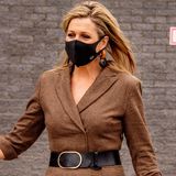 Für den Besuch der Hogeschool in Rotterdam setzt Königin Máxima auf einen eleganten und doch lässigen Look. Zum braunen Woll-Jumpsuit kombiniert die Monarchin einen breiten Taillengürtel sowie Pumps und Henkeltasche. Das Outfit ist durchdacht und steht ihr hervorragend und doch hat sie an diesem Tag mit einem Detail mächtig zu kämpfen.