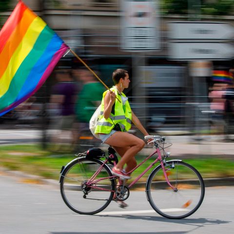 Pride Week: Deswegen ist sie uns so wichtig, Regenbogenfahne, Fahrradfahrerin