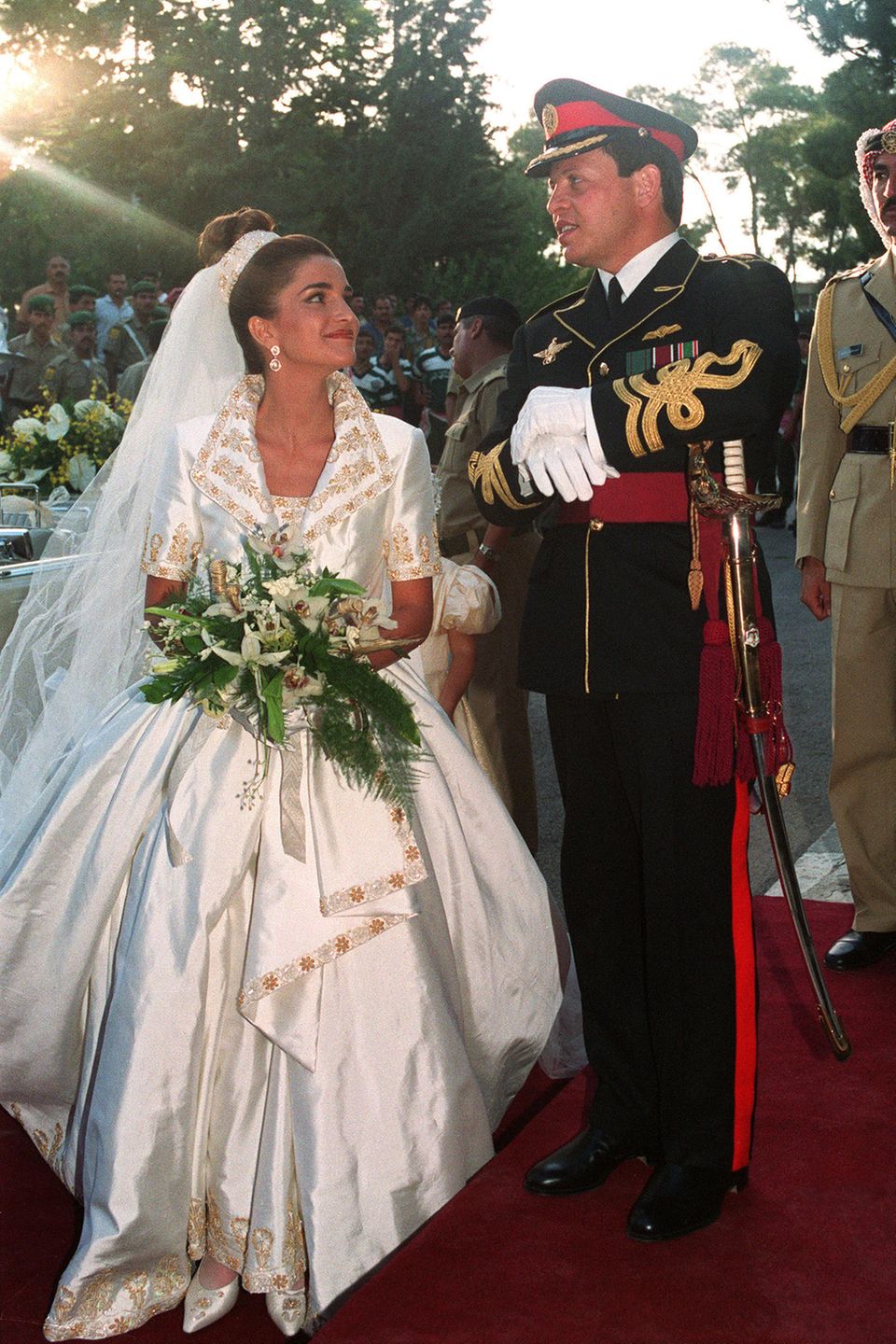 10. Juni 1993  Traumhochzeit im Königreich Jordanien: Prinz Abdullah heiratet seine Angebetete Rania Yasin im Königlichen Palast in Amman, und die zukünftige Königin strahlt dabei in einem schimmernden Satinkleid mit Jäckchen mit großem Kragen und aufwendigen, gold-floralen Stickereien.