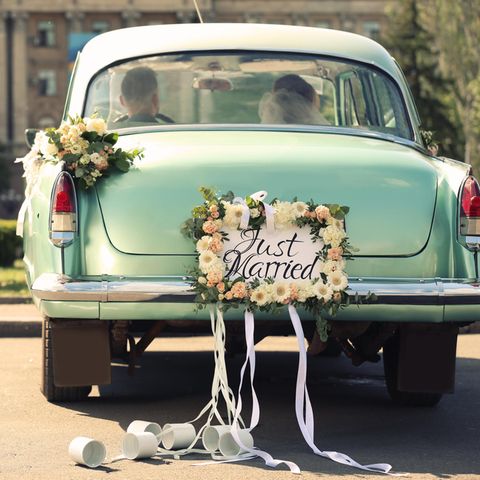 Autoschmuck Hochzeit: So dekorieren Sie das Brautauto, Brautpaar sitzt in geschmücktem Hochzeitsauto