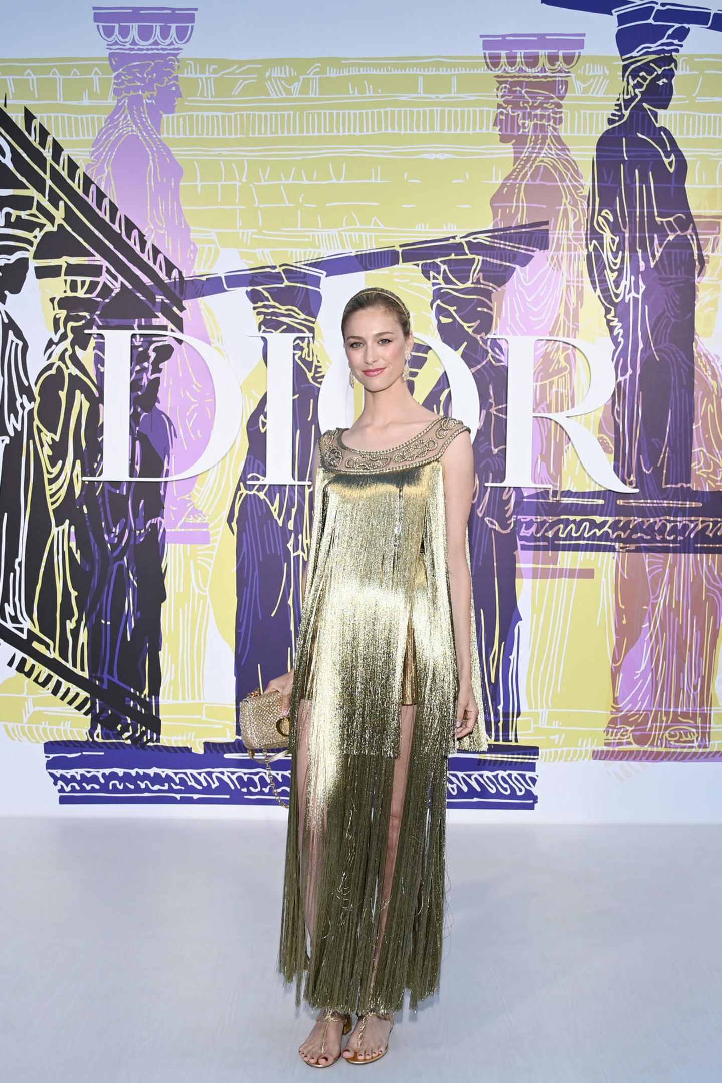 Von der Prinzessin zur Göttin: Beatrice Borromeo trägt ein goldenes Fransenkleid, Sandalen und eine elegante Hochsteckfrisur. Stilsicher und selbstbewusst posiert sie vor der Show für die Fotografen. 