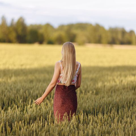 Zeckenbiss erkennen: Junge Frau läuft durch ein Getreidefeld