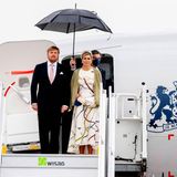Berlin zeigt sich bei der Ankunft von König Willem-Alexander und Königin Máxima nicht von seiner besten Seite: Der Himmel ist grau und ein Regenschirm muss das niederländische Königspaar vor Nässe schützen. Dafür ist auf Máximas modisches Gespür Verlass. Sie trägt ein weißes Kleid mit auffälligem Muster, das sich auch auf ihrem Haarreifen wiederfindet. Darüber wählt die Mutter von drei Töchtern einen grünen Cardigan.