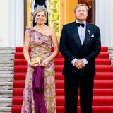 Königin Máxima und König Willem-Alexander haben sich zum Staatsbesuch in Berlin in Schale geworfen. Nicht nur das fliederfarbene Abendkleid von Jan Taminiau mit 3D-Blumen-Applikationen und einem One-Shoulder-Schnitt ist ein Meisterwerk. Auch die Juwelen, die Máxima für den Abend wählt, ziehen alle Blicke auf sich. Dazu setzt die Mutter von drei Töchtern auf eine Clutch von Begum Khan in Gold mit einem aufgestickten "Evil Eye". Doch es wartet noch ein weiteres Highlight ...