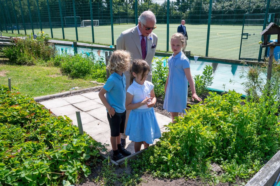 Vom Strand aus geht es für das Herzogenpaar weiter zur Five Islands Academy. Hier präsentieren die Schüler:innen Prinz Charles stolz den eigenen Gemüsegarten und Charles lässt sich geduldig über den Schulhof führen. Vom Strand aus geht es für das Herzogenpaar weiter zur Five Islands Academy. Hier präsentieren die Schüler:innen Prinz Charles stolz den eigenen Gemüsegarten und Charles lässt sich geduldig über den Schulhof führen.