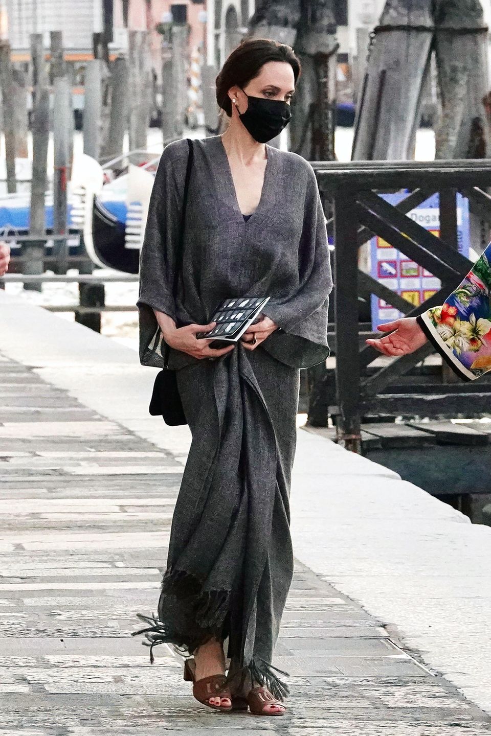 Wenn Angelina Jolie unterwegs ist, passiert das selten ohne das perfekte Outfit. Auch in Venedig zeigt sich die Schauspielerin edel und stilsicher, wie immer. Auf dem Weg zum Wassertaxi setzt sie auf einen bodenlangen Kaftan in dramatischem Grau und Sandaletten mit Blockabsatz von Chanel. Besonders passend: die Perlenohrringe zum eleganten Dutt.
