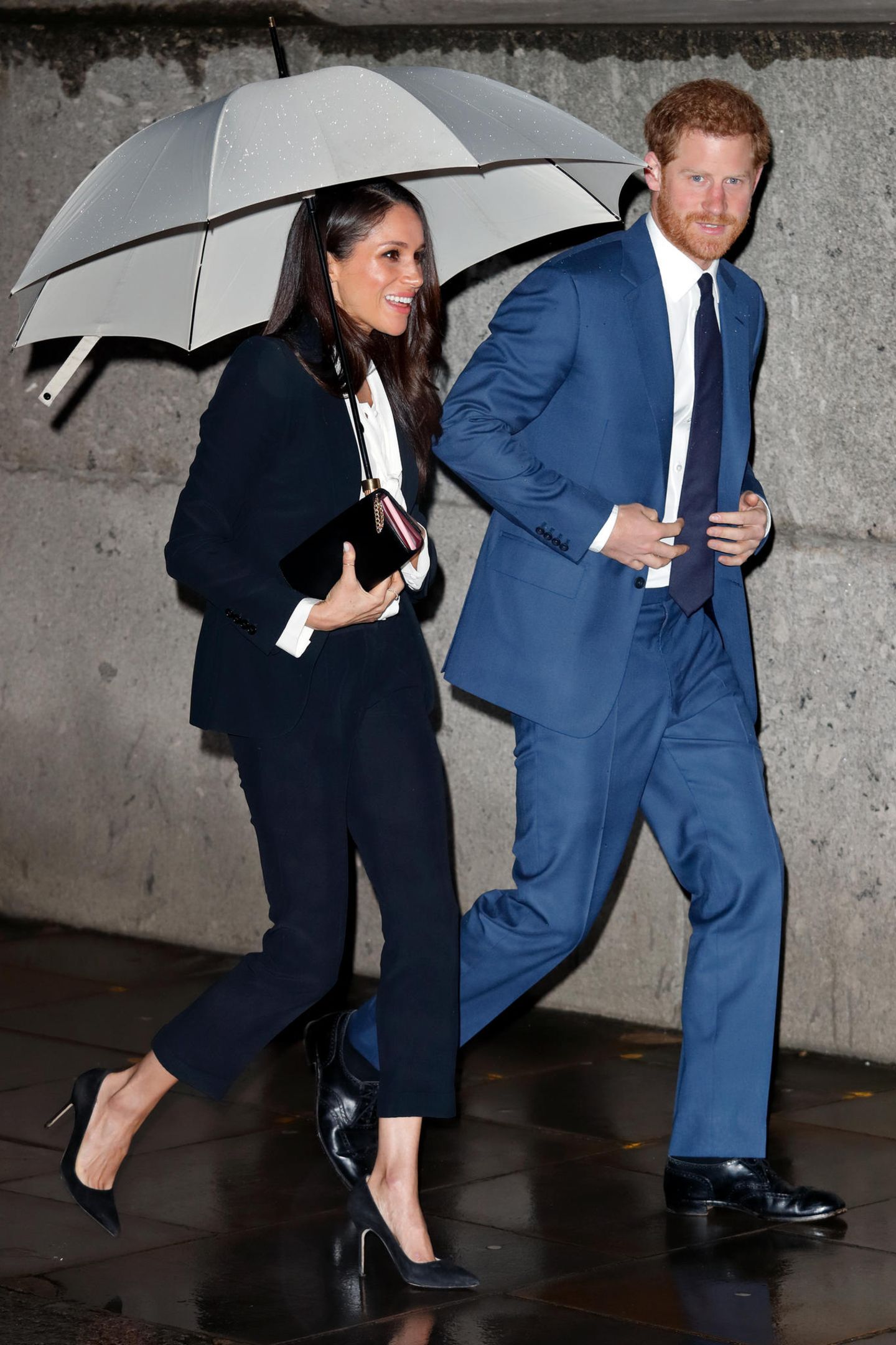 Prinz Harry und Meghan Markle laufen im Regen nebeneinander her.