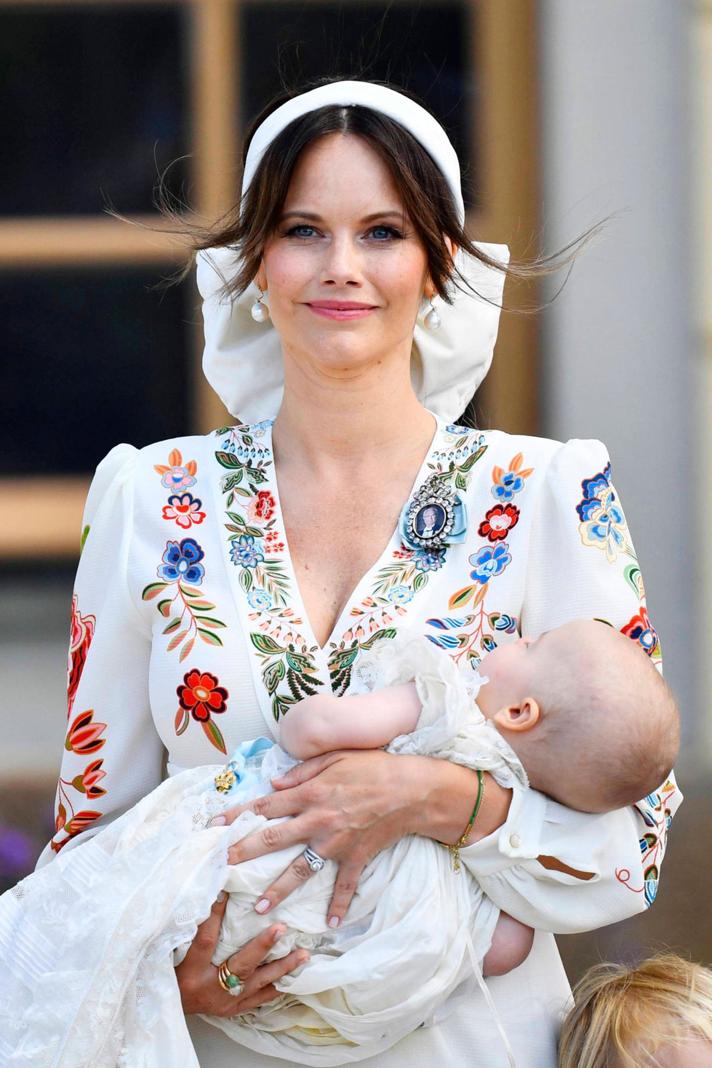 Prinzessin Sofia erscheint zur Taufe ihres jüngsten Sohnes Prinz Julian in einem weißen Kleid mit auffälligen Blumenmuster. Ein Haarband mit XL-Schleife ziert den Kopf der Dreifach-Mama, Perlenohrringe und ein pinkfarbener Lippenstift runden den Look ab. 