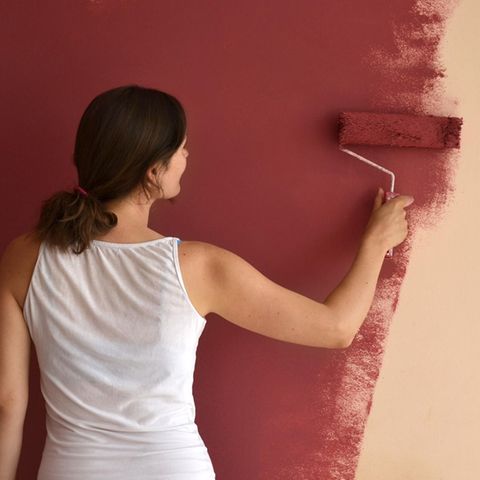 Wandfarbe: Frau streicht eine Wand rot