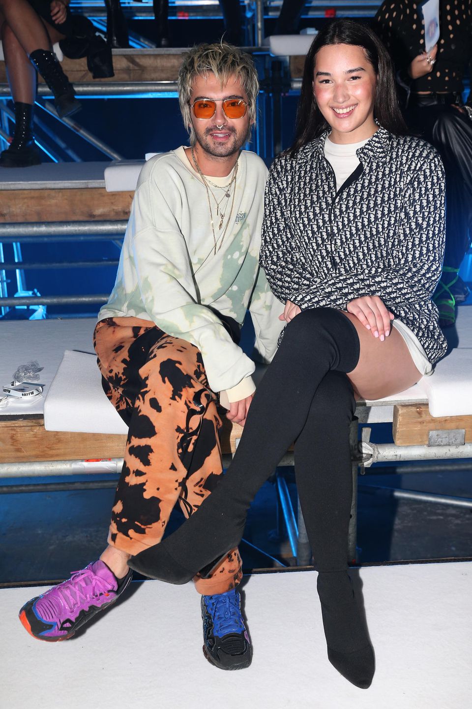 Bill Kaulitz und Alex Mariah Peter, die Gewinnerin der diesjährigen ''Germany's next Topmodel''-Staffel (v.l.n.r), nehmen in der Front-row der ''Leni Klum X About You''-Show Platz. Vor dem Start der Show posieren die beiden lächelnd für die Kameras.