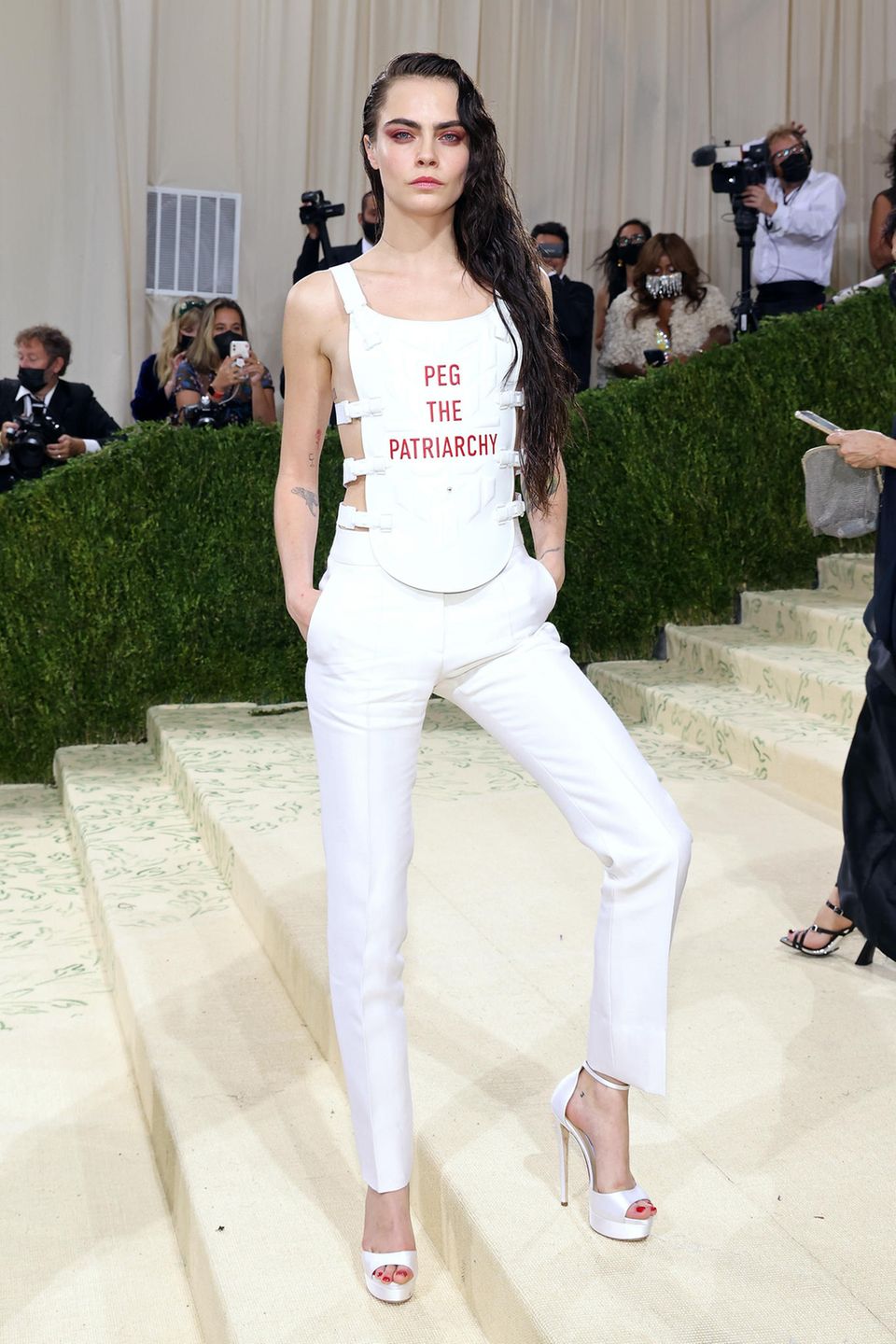 Auch Cara Delevingne nutzt die berühmten Stufen vor dem Metropolitan Museum of Art für Ansagen und setzt in ihrem weißen Dior-Look mit dem Spruch "Peg the Patriarchy" ein feministisches Statement.