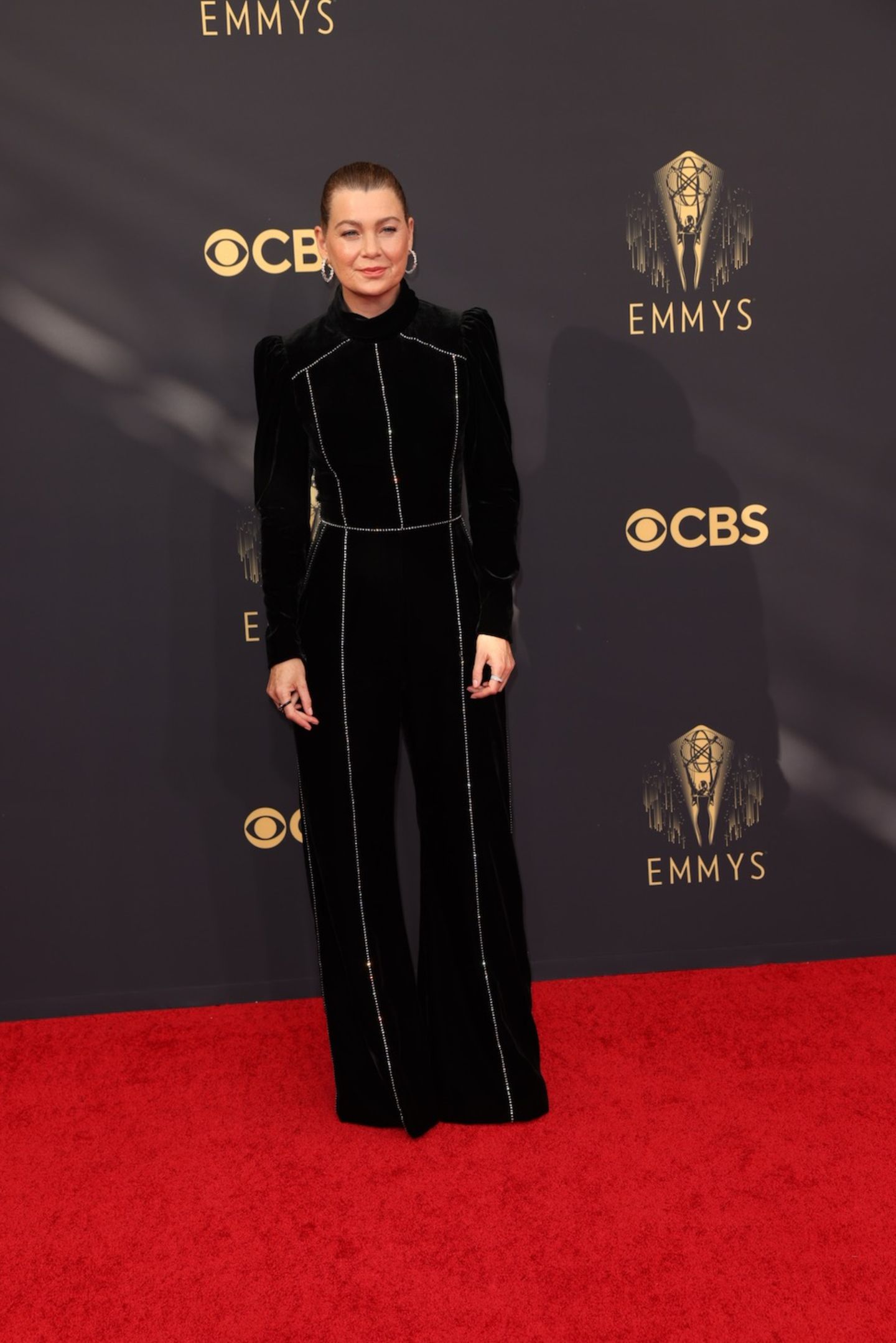 Hochgeschlossen, aber nicht minder sexy. "Grey's Anatomy"-Star Ellen Pompeo erscheint in einem schwarzen Samt-Kleid mit Strass-Applikationen bei den Emmy Awards 2021. Passend dazu trägt sie ihre Haare streng zu einem Zopf gebunden.