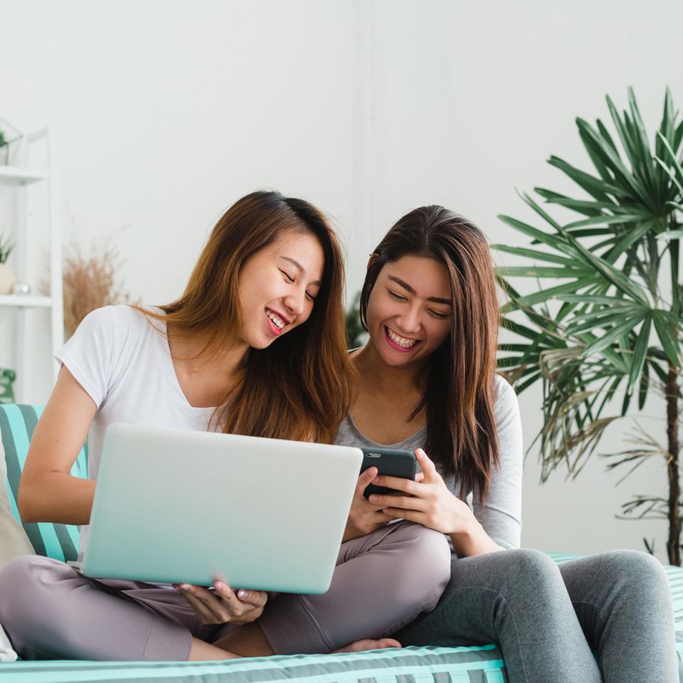 Black Friday 2022: Das erwartet Sie, Zwei junge Frauen sitzen auf dem Sofa und machen Online-Shopping