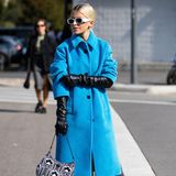 Caro Daur ist eine eche Trendsetterin und in den Modemetropolen dieser Welt zu Hause. Bei der Fashion Week in Mailand besucht sie die Frühjahr/Sommer 2022-Show von Prada. Passend zum Anlass greift die Influencerin zu einer Henkeltasche des italienischen Labels. Durch einen blauen Mantel und schwarzen Lederhandschuhen wird der Look abgerundet. 