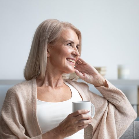 Frauen ab 50: Ältere Frau sitz auf Sofa und trinkt Tee
