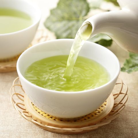 Grüner Tee wird in einen weißen Porzellanbecher eingegossen.