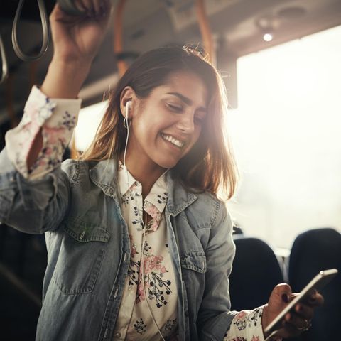 Musikgeschmack & Persönlichkeit: Frau hört im Bus Musik auf dem Smartphone.