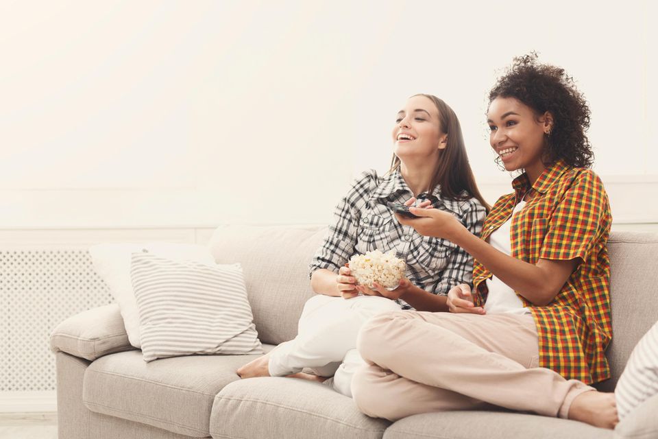 Was Ihre Lieblingsserie über Ihren Charakter enthüllt: Zwei Frauen schauen lachend Fernsehen.