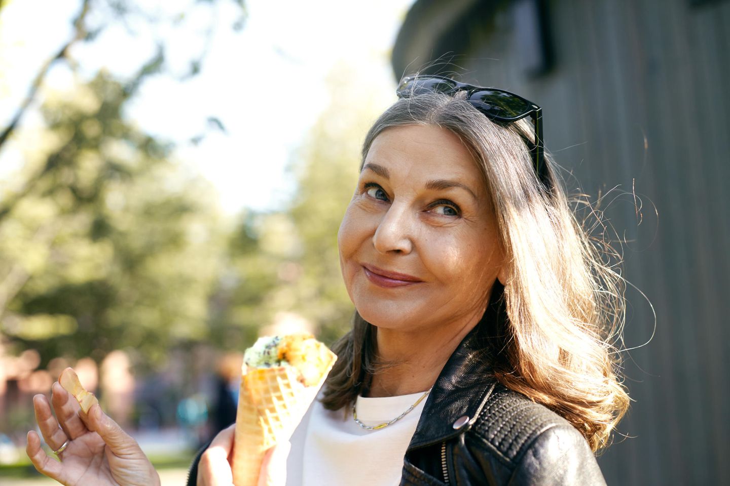 6 Lebensmittel, die Ihre Wechseljahre verschlimmern können: Frau mittleren Alters isst draußen ein Eis.